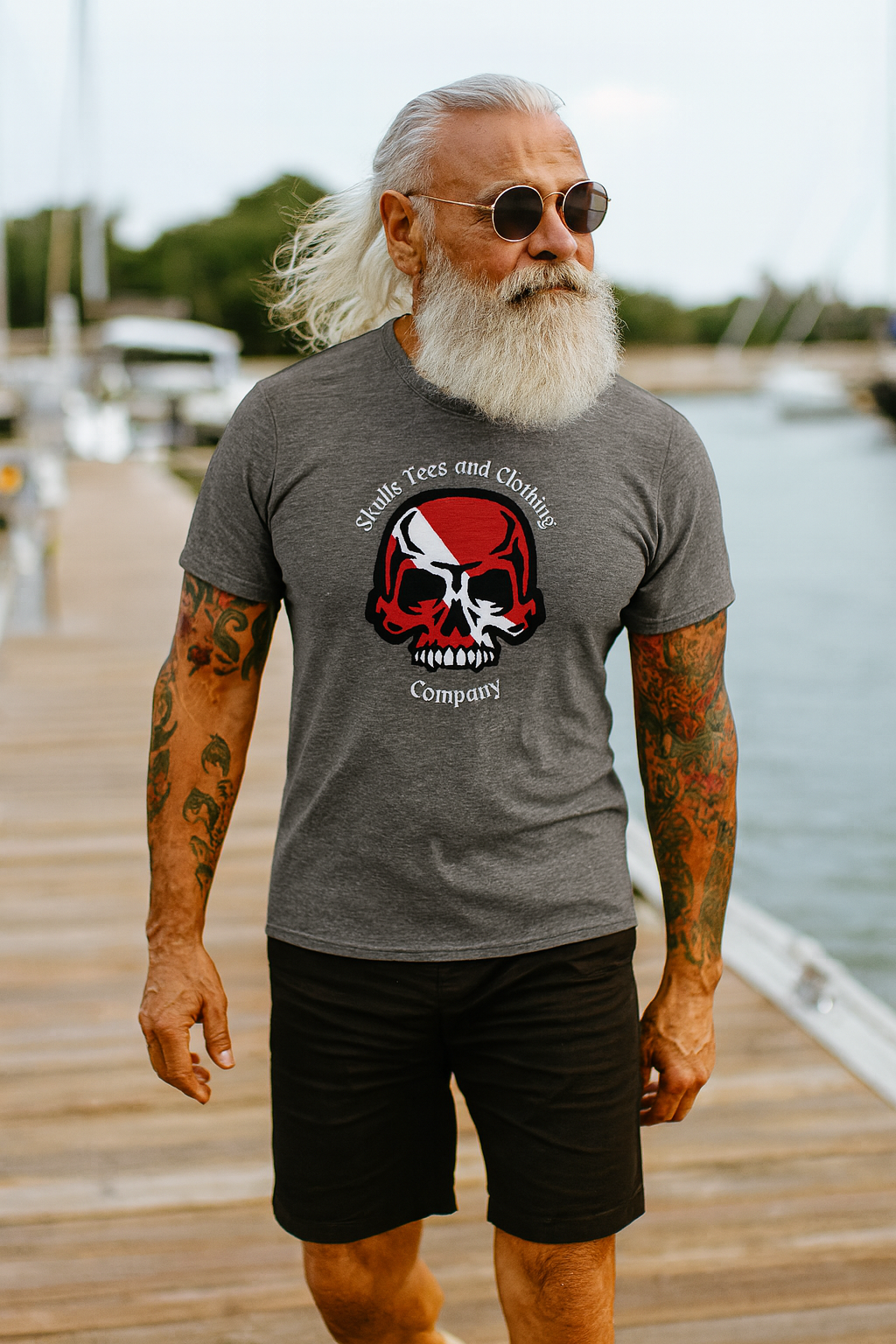 Man wearing a gray t-shirt with a logo on a dock by water